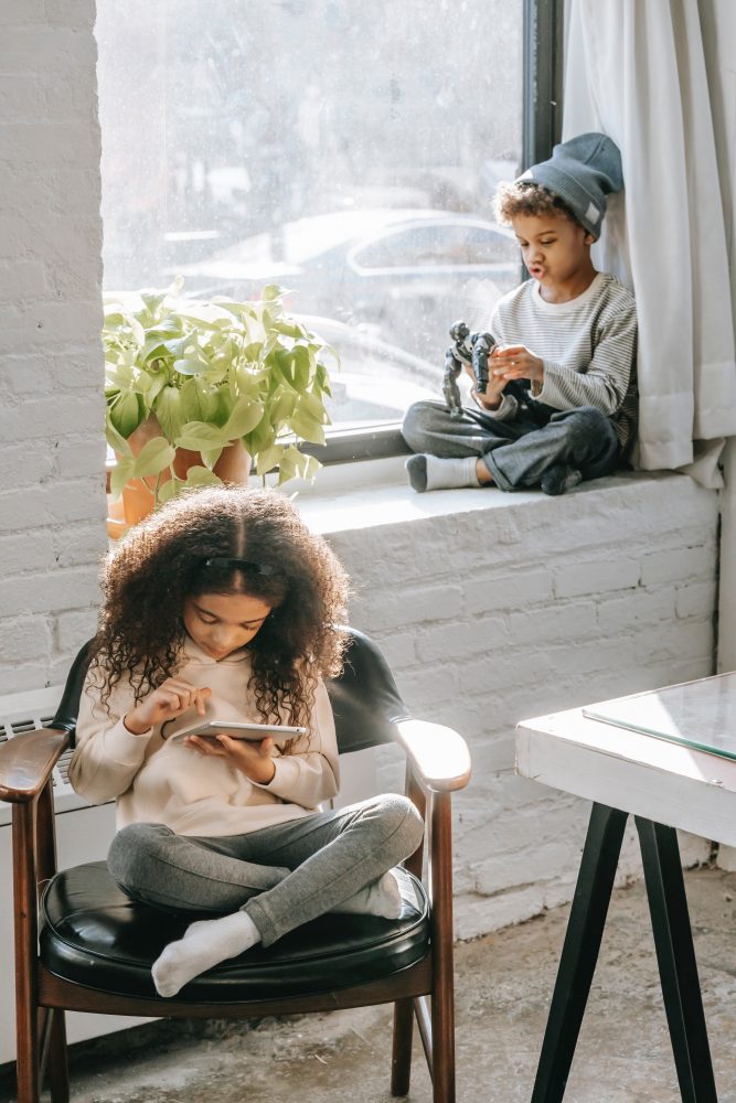 https://www.pexels.com/photo/cute-ethnic-kid-playing-on-windowsill-near-sister-surfing-tablet-during-weekend-at-home-6437811/